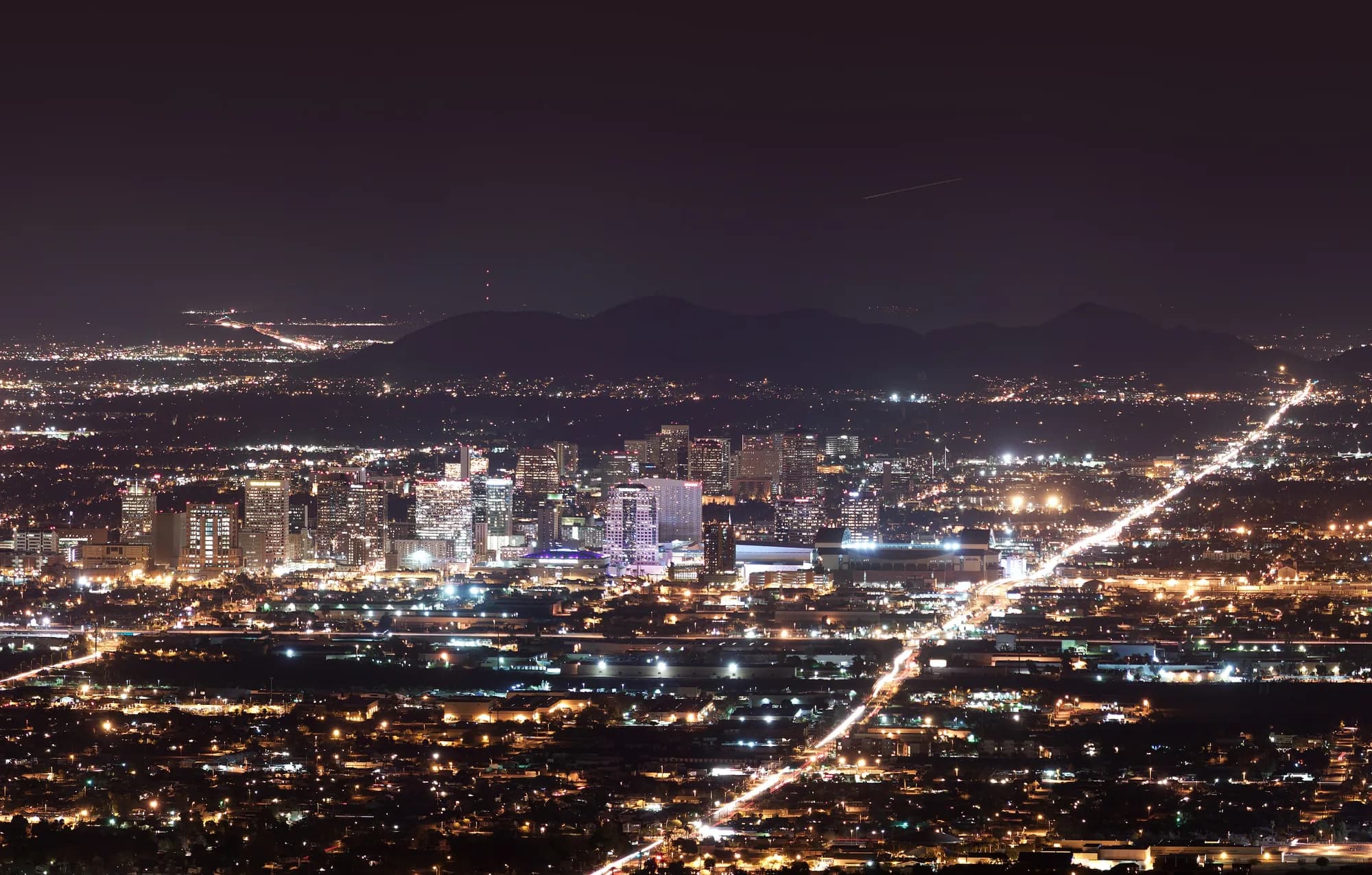 Downtown Phoenix skyline at night with the mountains behind