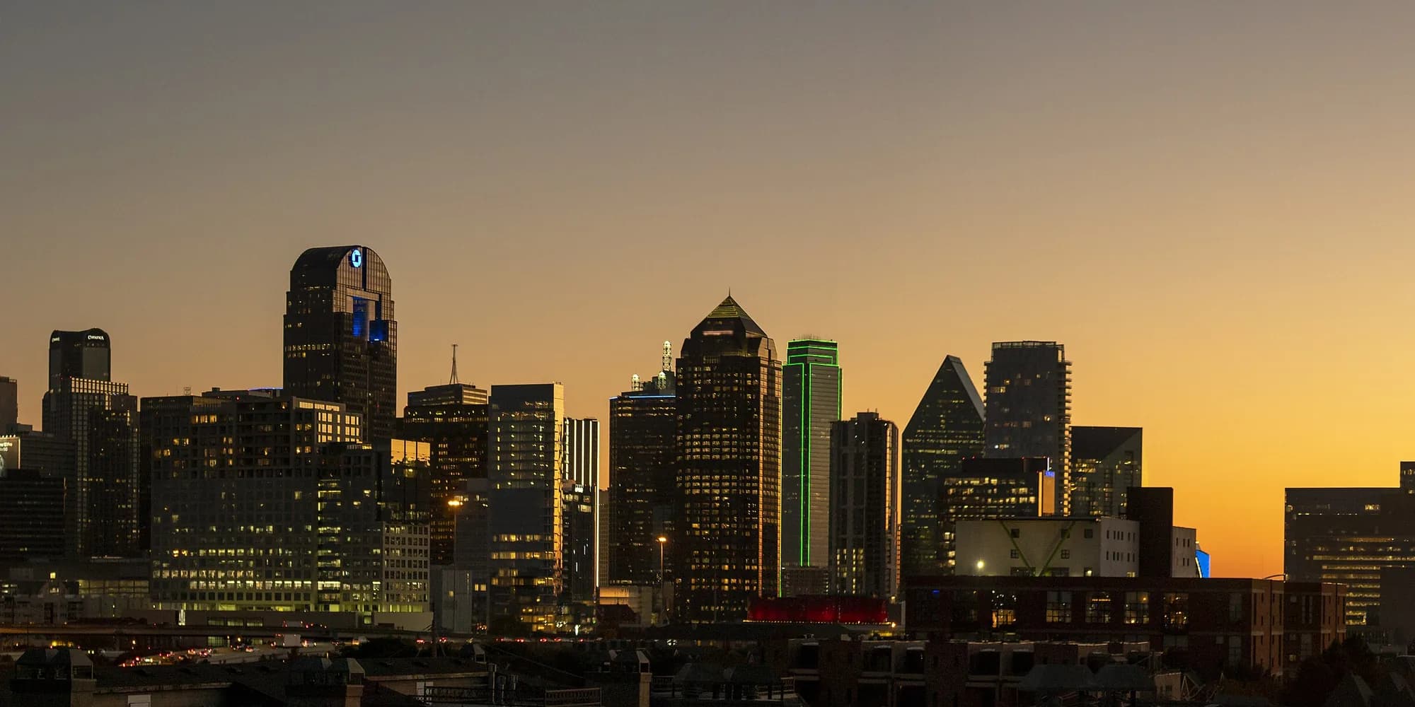 Dallas skyline silhouetted against an orange dusk sky
