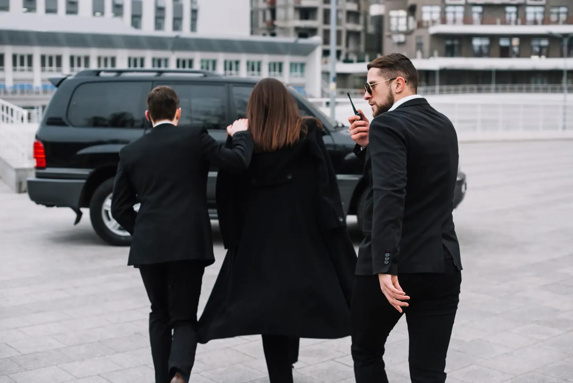 Protection agents discreetly escorting a client to a waiting vehicle