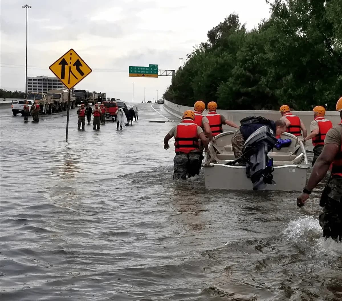 Response personnel guiding a rescue boat through flooded highway lanes