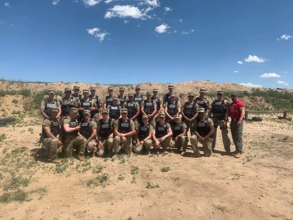 Graduating class of security officers in tactical vests at an outdoor training range