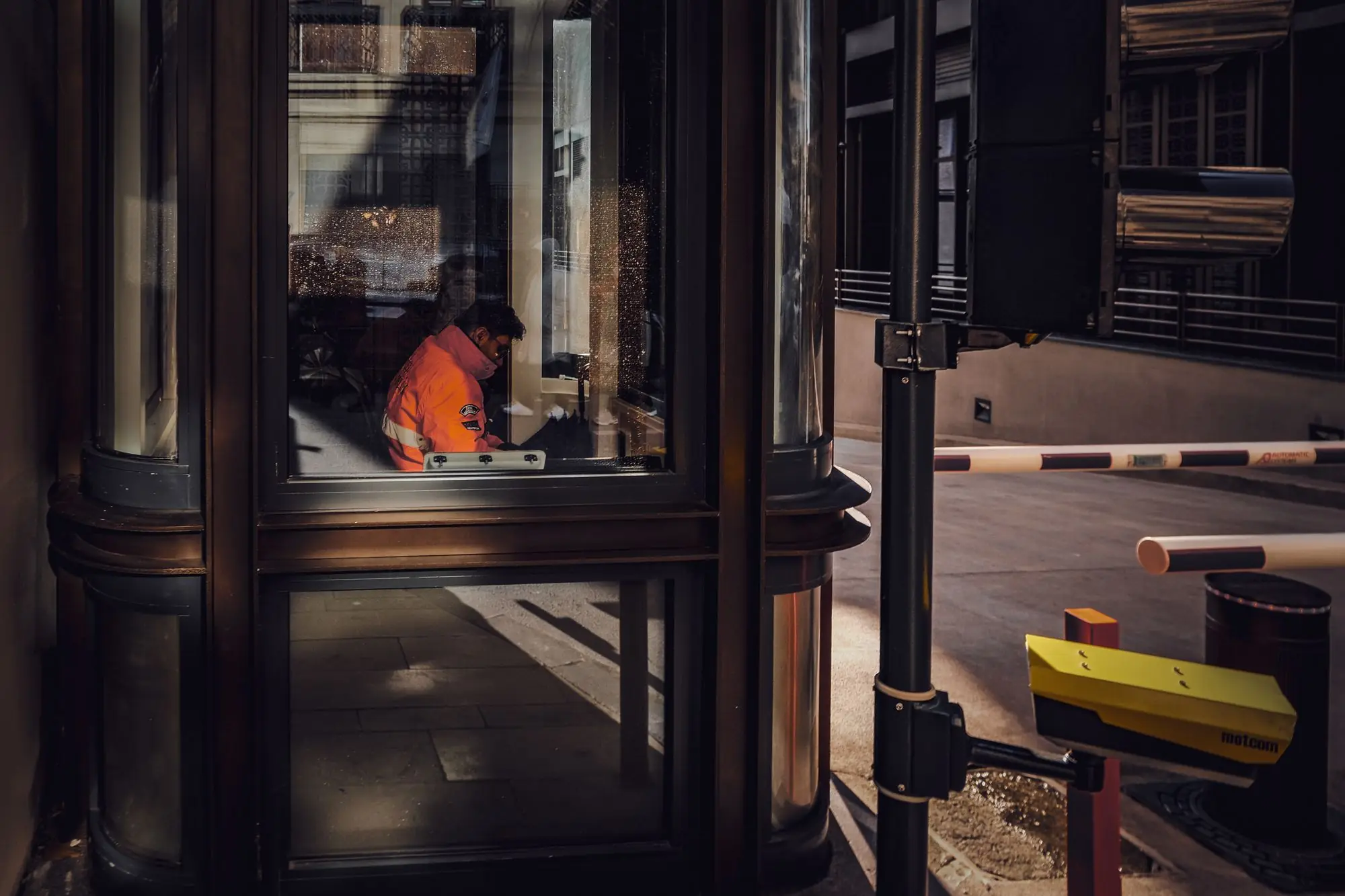 Guard booth and barrier arm controlling vehicle access to a facility at night