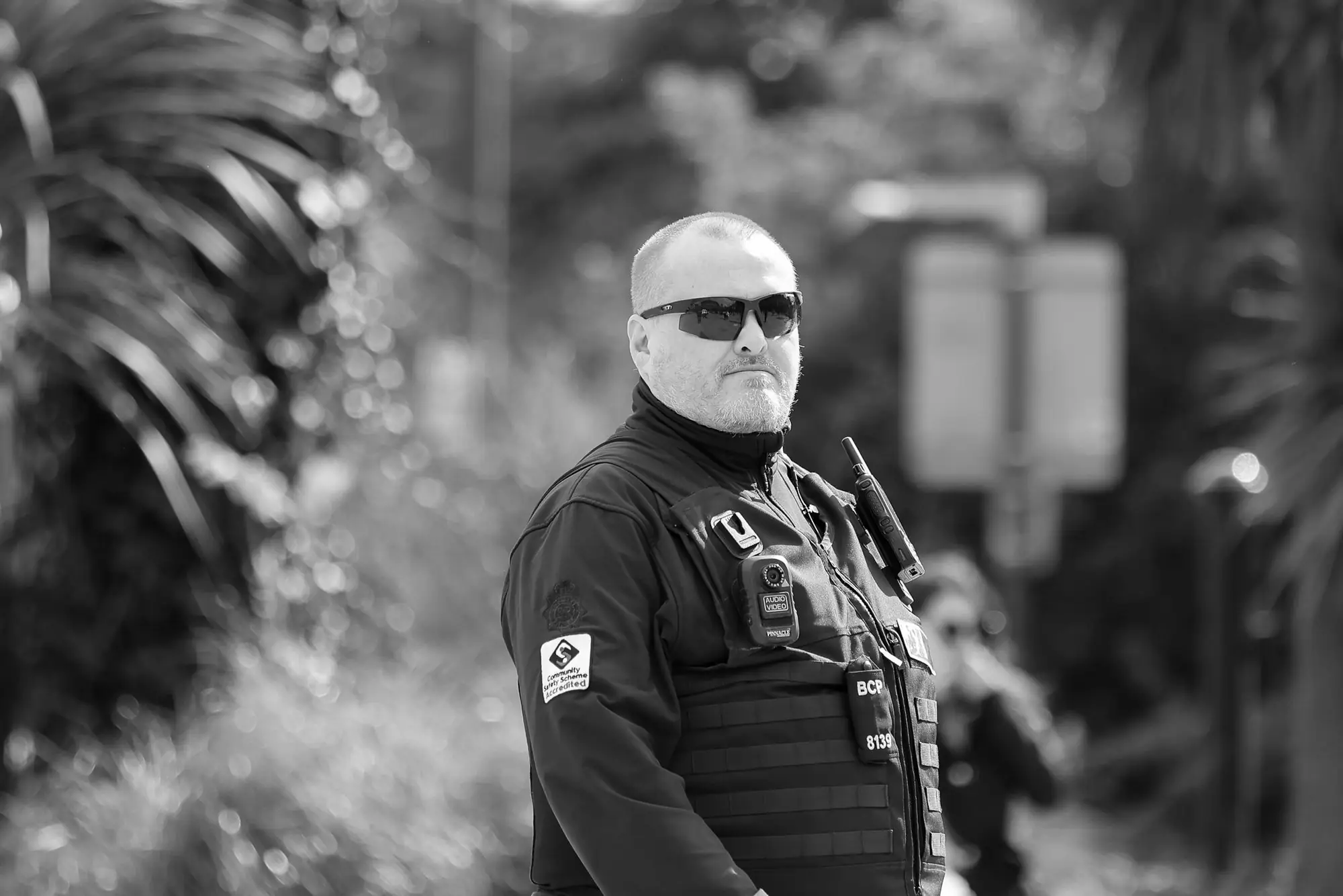 Security officer in a tactical vest with radio standing watch on an outdoor assignment