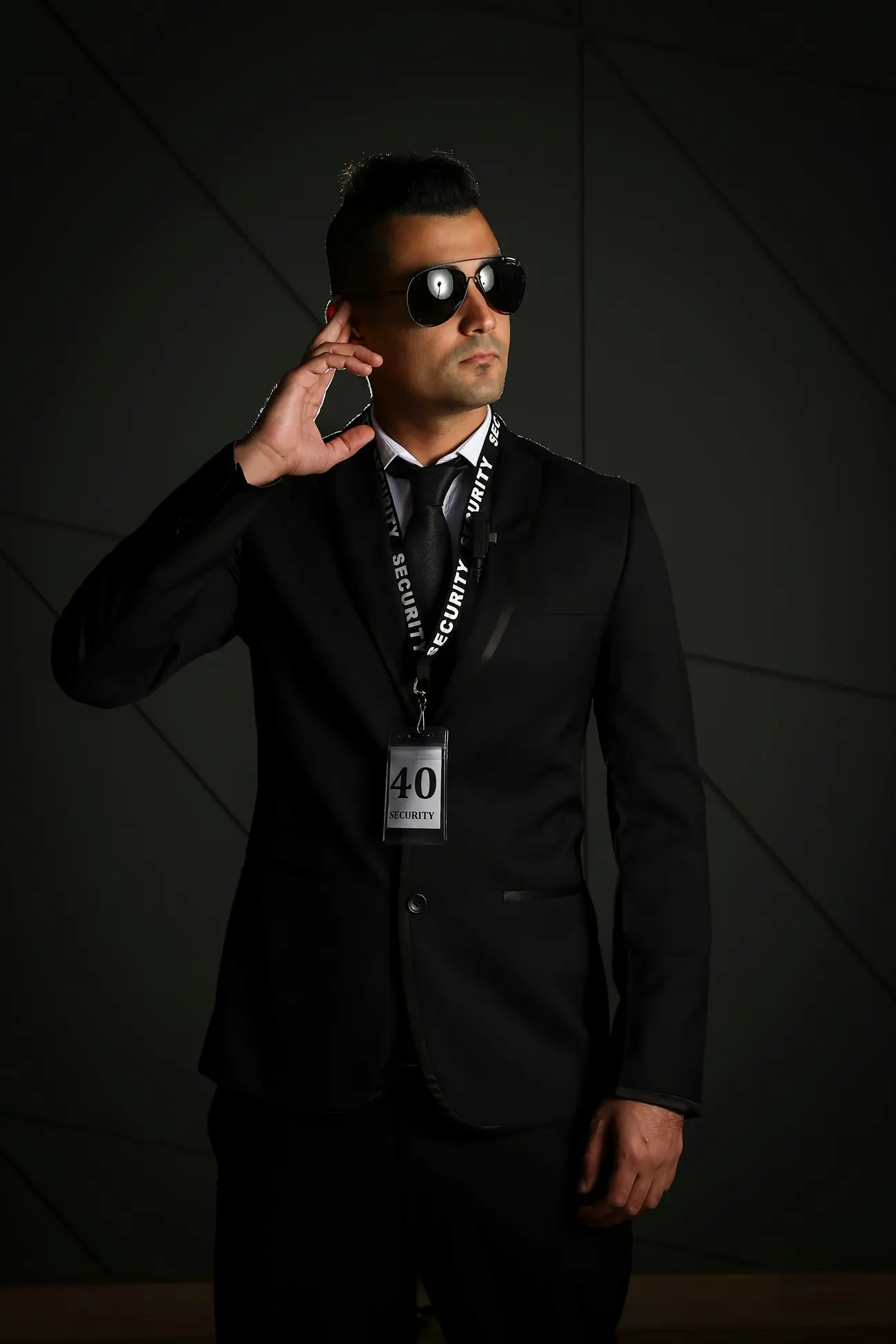 Close protection officer in a dark suit and sunglasses listening to an earpiece