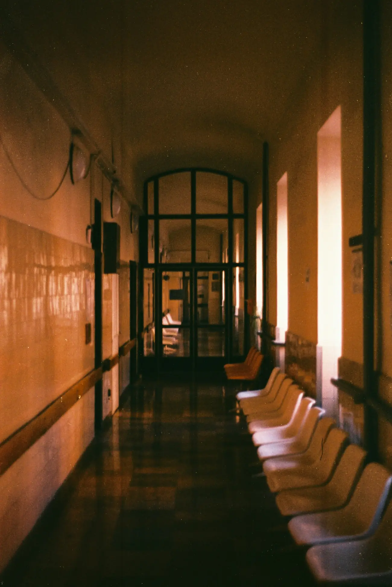 Quiet hospital corridor with waiting-area chairs in low light