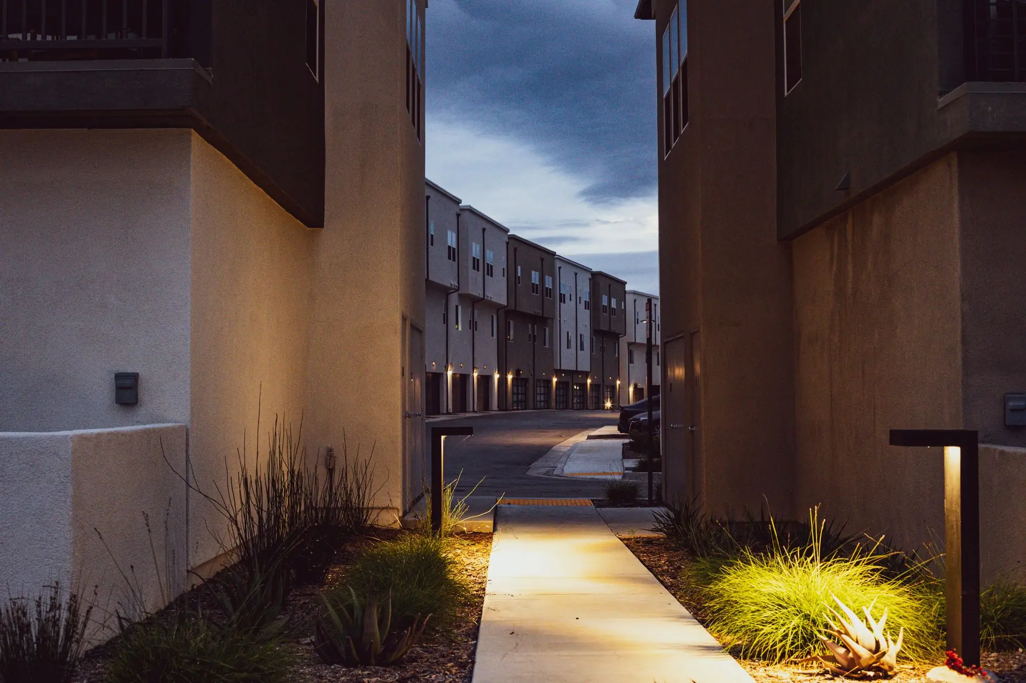 Lit walkway between apartment buildings at blue hour
