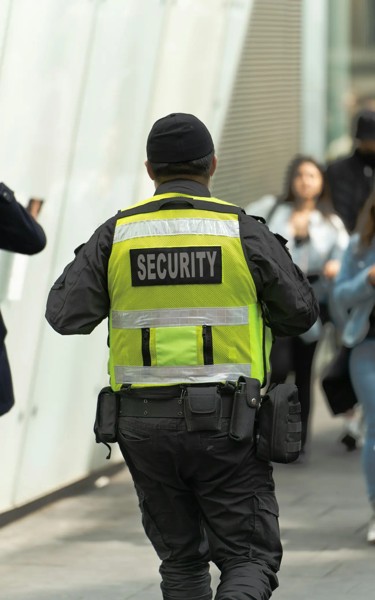 Security officer in a high-visibility vest patrolling a busy corridor