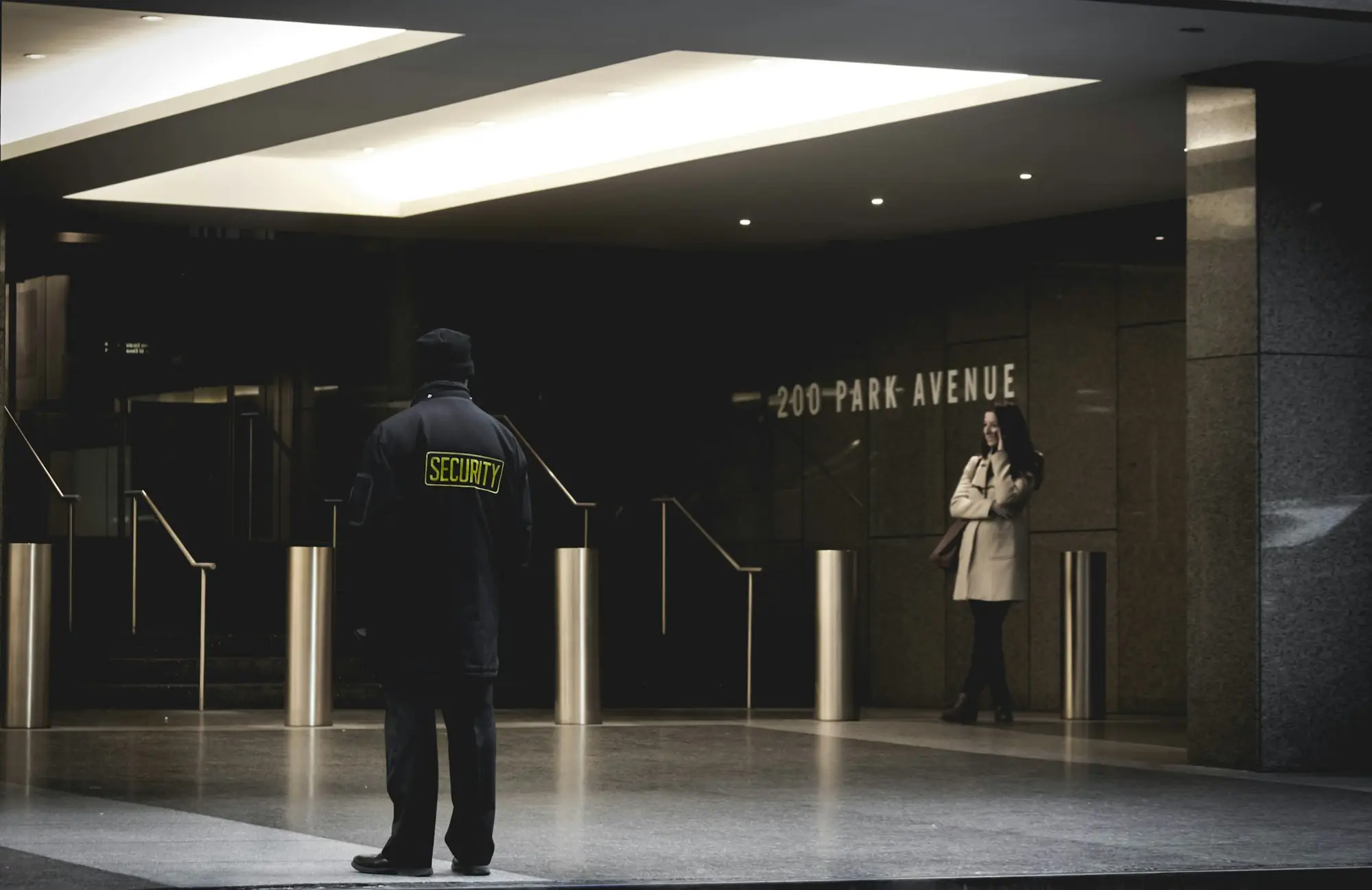 Uniformed security officer standing watch at the turnstiles of a corporate lobby